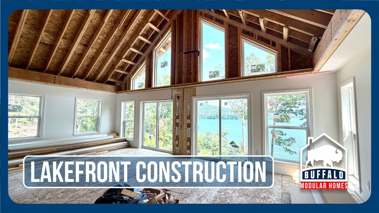 Lakefront modular home under construction with a wall of windows facing the lake